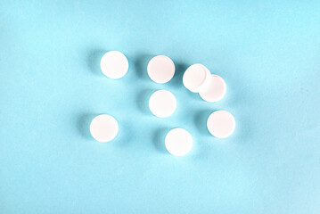 many different white pills on blue background. Assorted pharmaceutical medicine tablets, prescription drugs.