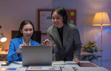 Two happy Asian businesswomen Discuss financial document work starting a business Creative team brainstorming meeting, business partnership or teamwork concept of office colleagues.