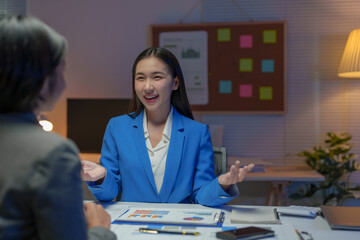 Two Asian businesswomen come up with an idea. Discuss investment projects and strategic planning with information via various documents and files. On a laptop computer at modern office.
