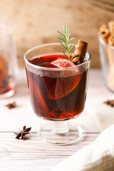 Glass of mulled wine with slices of orange and cinnamon sticks.