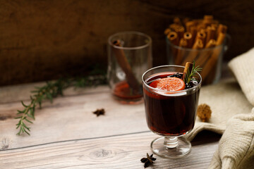 Glass of mulled wine with slices of orange and cinnamon sticks.