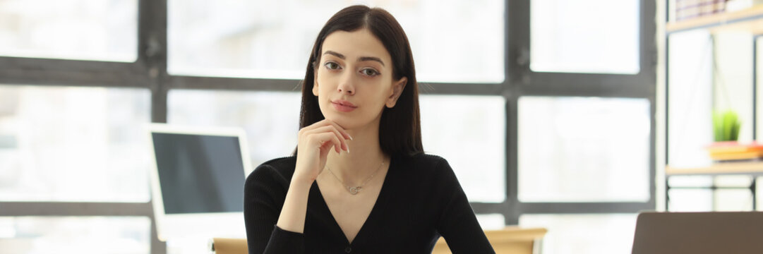 Pretty female worker looks forward at workplace in office