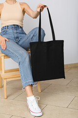 A woman is sitting on a chair with a bag in her hands
