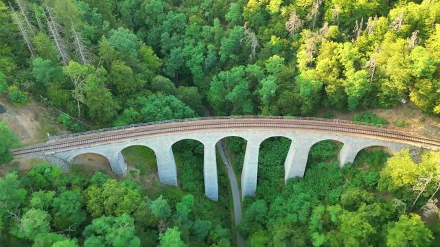 The Zampach railway bridge stands as the highest stone bridge in Czechia, nestled amid lush greenery. It showcases stunning architecture and impressive engineering against a natural backdrop.