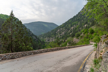 A road with a mountain in the background. The road is empty and the sky is cloudy.
