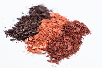 Scattered eye shadows in different shades. Cosmetics texture, white background.