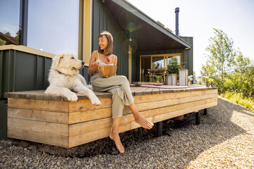 A woman enjoys a peaceful morning on the porch, sharing a moment with her loyal dog. The natural light and serene surroundings make this a perfect spot for relaxation.