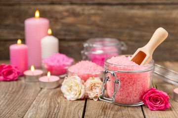 Sea salt for bath with aroma and rose flowers on textured wooden background. Pink sea salt. Spa treatments. Natural salt with herbs and essential oils. skincare concept. Meso for text. Copy space