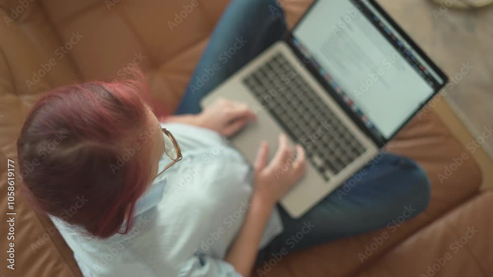 Poster a person is comfortably using their laptop while sitting on a couch, engaged in work as they take ad