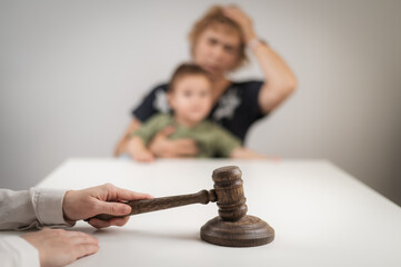 A judge hits a gavel against the backdrop of an elderly woman holding a child. 