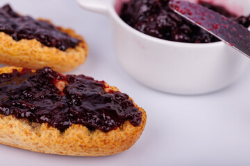 White background with toast and blueberry jam along with a jam jar, highlighting color and texture in a delicious breakfast display