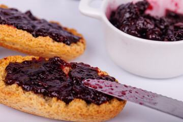 Toasts with blueberry jam beside a jam jar on a white background, capturing texture and color in a classic morning treat