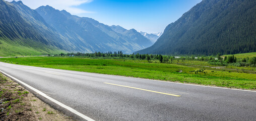 Countryside asphalt road and green meadow with mountains nature landscape on a sunny day. Road trip. - obrazy, fototapety, plakaty