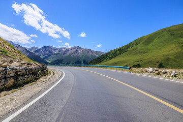 Asphalt highway road and mountain nature landscape under blue sky. Road trip.