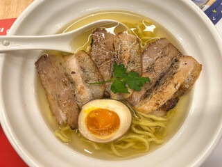 A delicious bowl filled with savory ramen soup that contains tender meat and noodles, accompanied by a spoon resting inside it