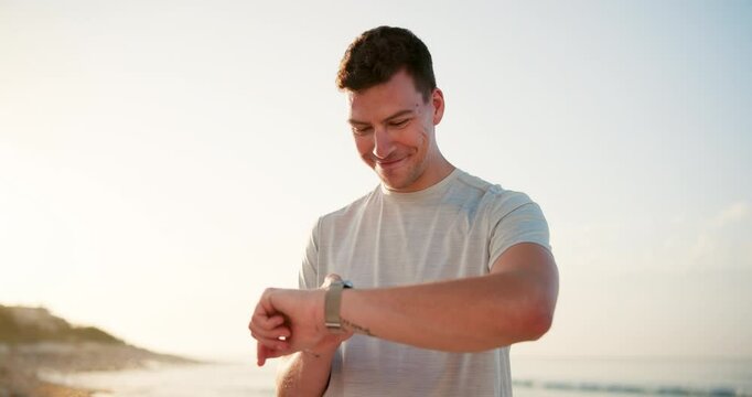 Happy man, fitness and beach with watch for workout app, tracker or step counter in nature. Young, male person or active runner with smile for wristwatch, performance or exercise goals on ocean coast