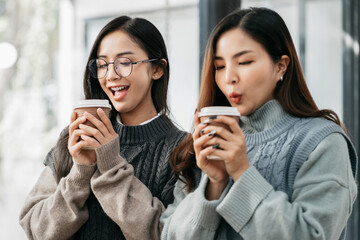 female colleague of half Asian descent holds a cup of coffee and smiles happily.