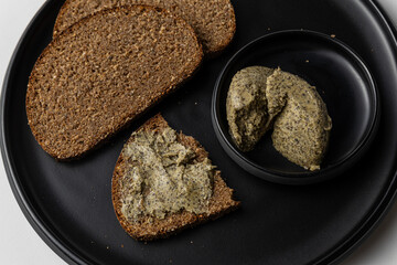 Sliced Rye Bread with Herb Butter on Black Plate