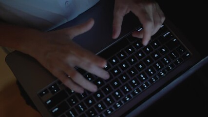 This image features a closeup shot that captures hands actively typing on a laptop keyboard, illuminated by low light, reflecting the essence of modern work, creativity, and professional efficiency