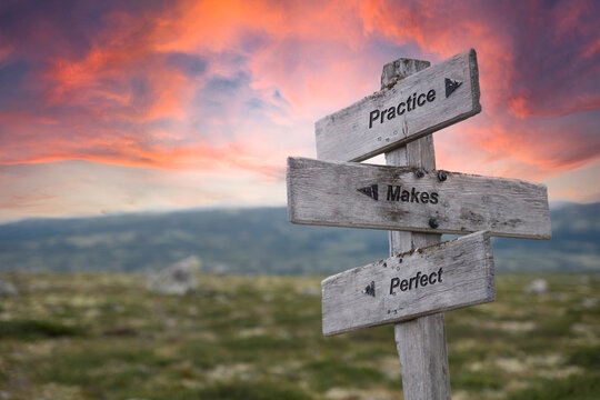 practice makes perfect text quote written on wooden signpost outdoors in nature. Red dramatic skies in the background