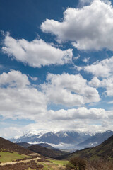 Obraz premium A village on the slopes of the mountain, cloudy sky, meadows and trees