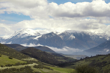 A village on the slopes of the mountain, cloudy sky, meadows and trees