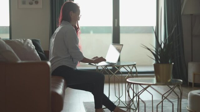 A woman works remotely from home on her laptop, utilizing natural light. She embodies the balance between career growth and personal life, demonstrating that success in both is achievable