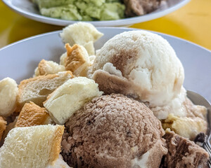 Coconut milk ice cream in a variety of flavors, a creamy and frozen summer dessert. Several scoops of ice in a bowl.