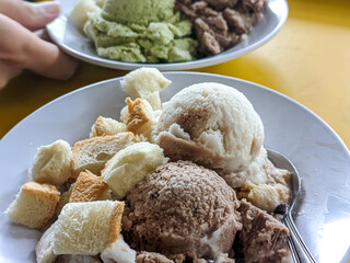 Coconut milk ice cream in a variety of flavors, a creamy and frozen summer dessert. Several scoops of ice in a bowl.