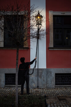 A lamplighter ignites gas lamps on Tumski Island in Wrocław, Poland, creating a magical ambiance as the historic surroundings glow in the evening light.