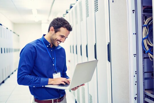 IT engineer using a laptop in a server room. - Powered by Adobe