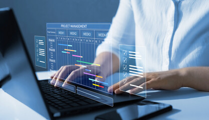 Business Project Management System.Project manager working on laptop and updating tasks and milestones progress planning with Gantt chart scheduling interface for company on virtual screen. 
