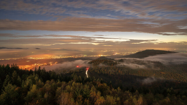 The clearing fog of an inversion uncovers the lights of the villages below in the Murg Valley in the northern Black Forest in Germany