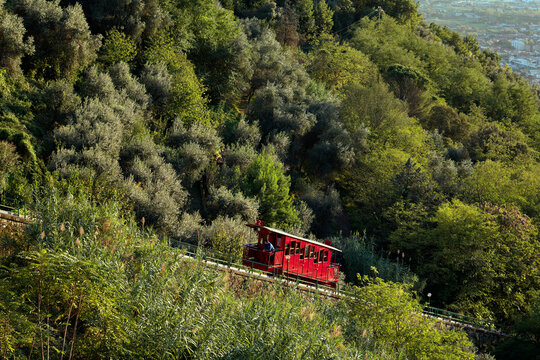 Funicolare di Montecatini Terme vista di lato con la carrozza rossa che sale verso Montecatini Alto, prossima alla stazione durante un tramonto.