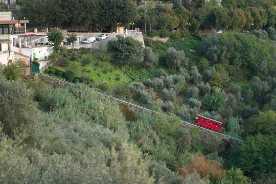 Funicolare di Montecatini Terme vista di lato con la carrozza rossa che sale verso Montecatini Alto, prossima alla stazione durante un tramonto.
