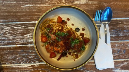 Delicious Italian pasta served on a white ceramic plate on a wooden table in a rustic setting.