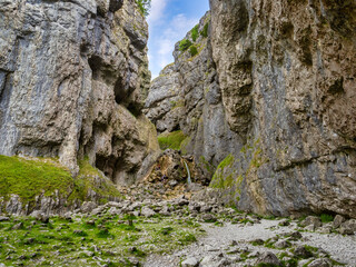 Obraz premium Gordale Scar, a limestone ravine with overhanging limestone cliffs over 330 feet high, Yorkshire Dales National Park, North Yorkshire, UK. This is the far end of the ravine, with its waterfall.