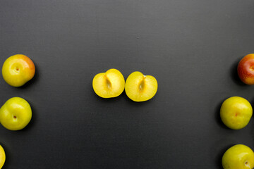 Fresh green plum fruit on dark background.