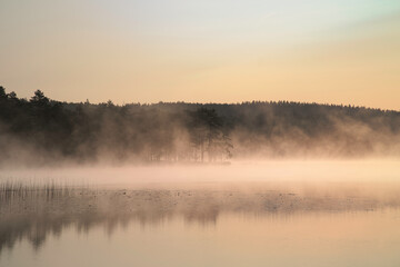 Sunrise with fog forming over a lake in Sweden, at dawn. Romantic silence