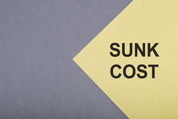 A yellow card with the words Sunk Cost written in black letters, positioned on a gray background.