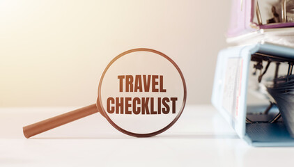 A magnifying glass hovering over the words travel checklist, emphasizing the importance of planning and organization before embarking on a trip.