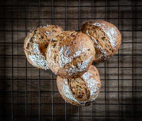 Four classic farm country bread buns on a grill. These homemade rustic rolls balls are made of organic wholemeal multigrain wheat flour for a sourdough recipe.