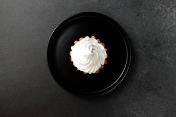 cake basket with protein cream in a black round plate on a black background