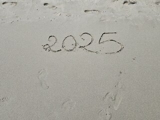 top view of year 2025 written on beach sand