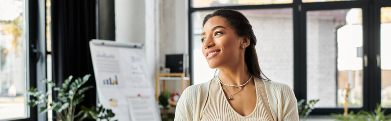 Bright natural light illuminates a young woman as she engages thoughtfully in her work environment.