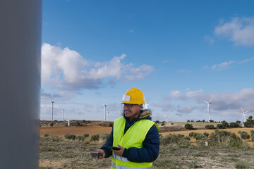 Wind turbine engineer inspecting a wind farm using mobile devices