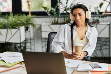 Fototapeta premium A confident young woman sips coffee during an online meeting in her stylish office.