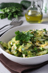 Salad with squid, cucumber, egg and green onion dressed with olive oil in white bowl