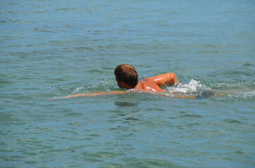 A guy swims into the sea with a breaststroke.