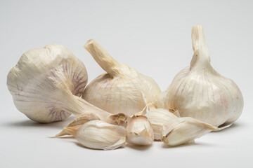 , Deutschland, 01.11.2024,  Nahaufnahme von frischem, ungeschältem Knoblauch und Knoblauchzehen auf einem weißen Hintergrund.